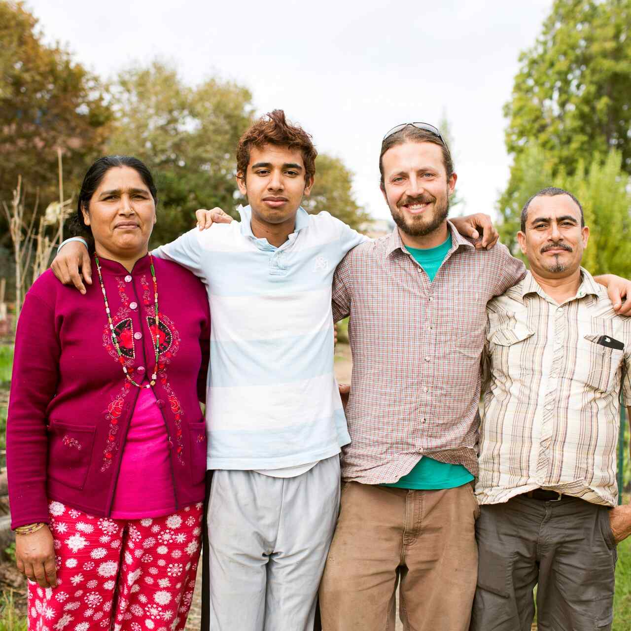 Four people pose for a picture outdoors in a garden.