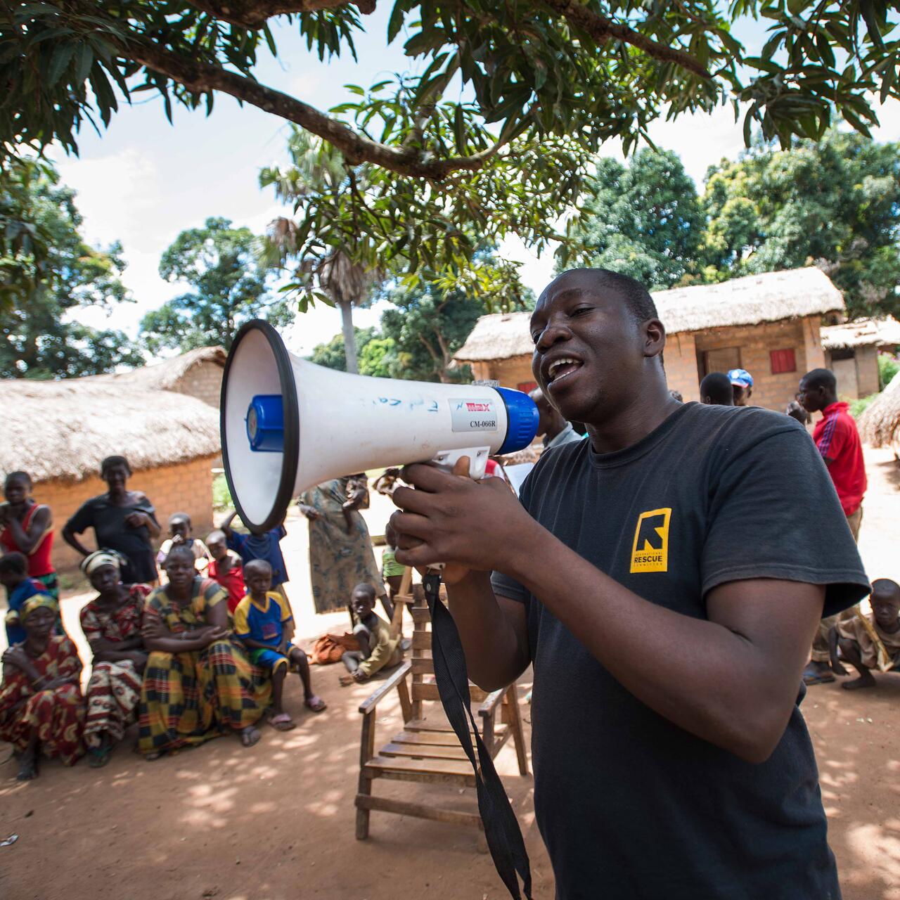 A man shouts to people surrounding him with a megaphone