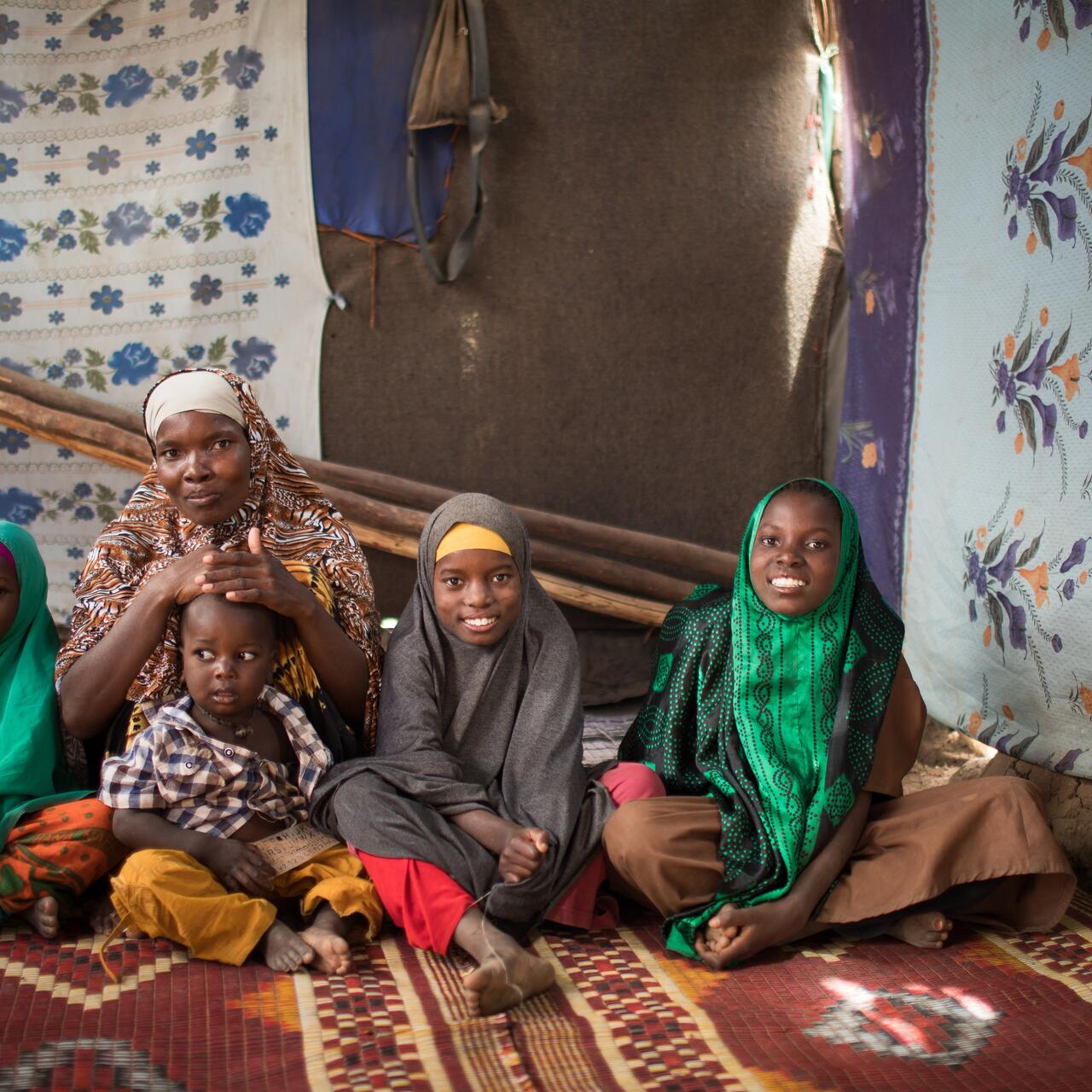 A mother with her four children sitting on a carpet