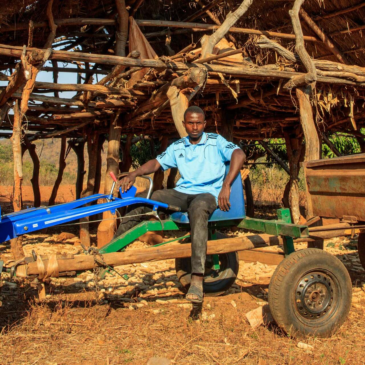 A man sits on a large tractor outside in Zimbabwe.