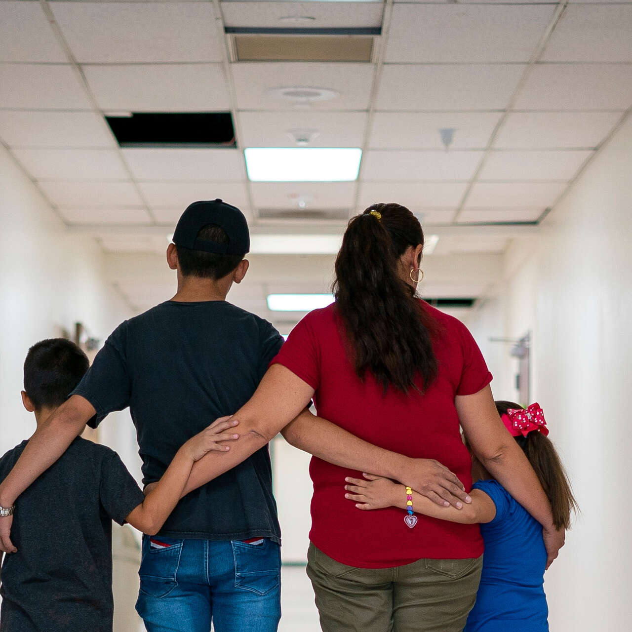 A family of four embrace each other with their backs turned to the camera.