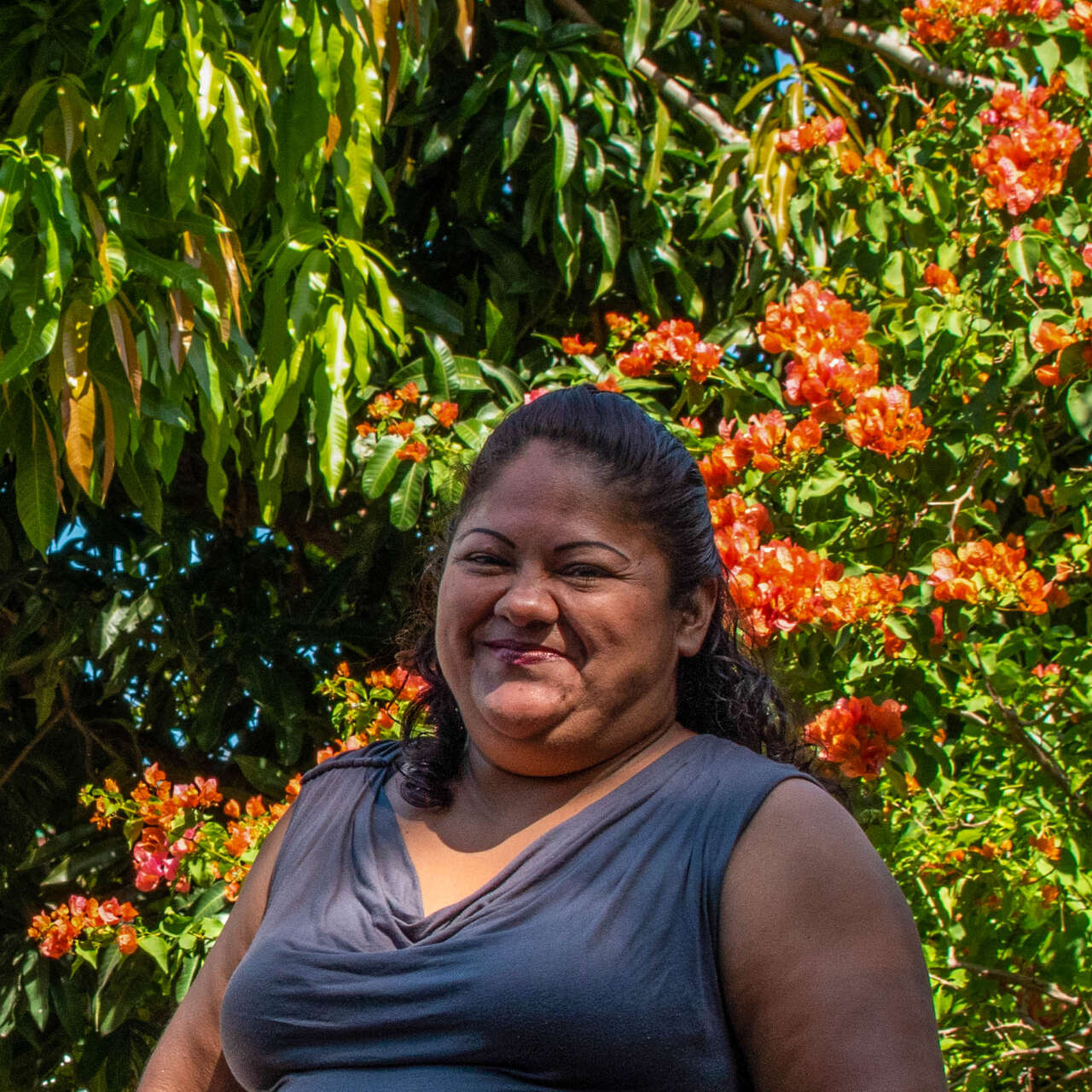 A woman stands in front of a blossoming tree and smiles for a photo.