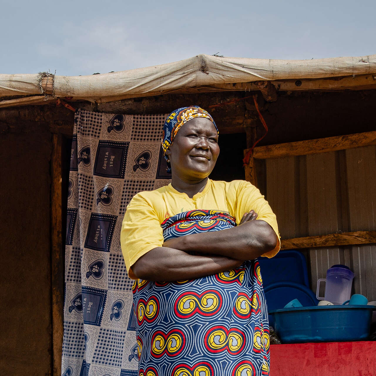 A woman stands with her arms folded outside in Uganda.