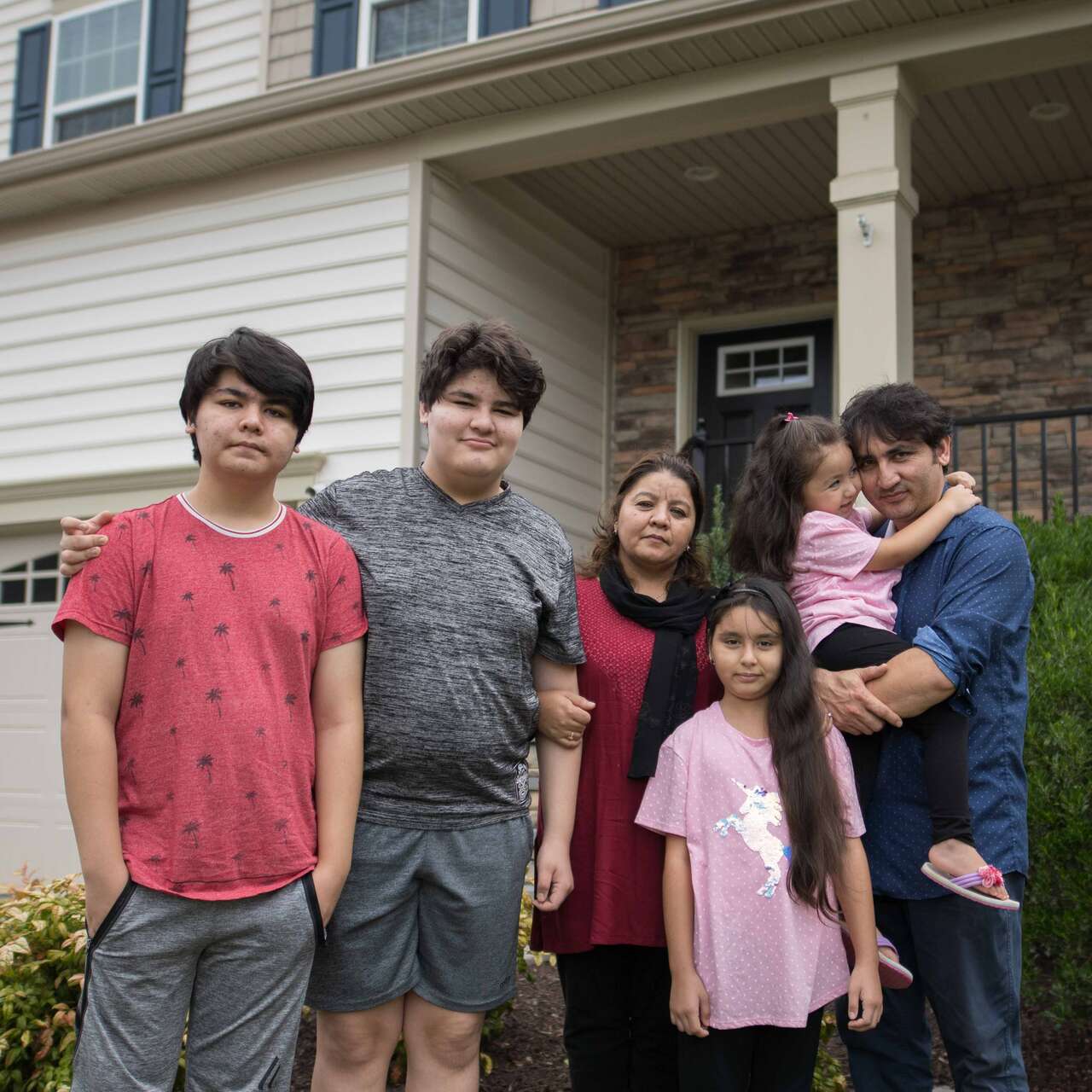 An Afghan family stands outside their home in Richmond.