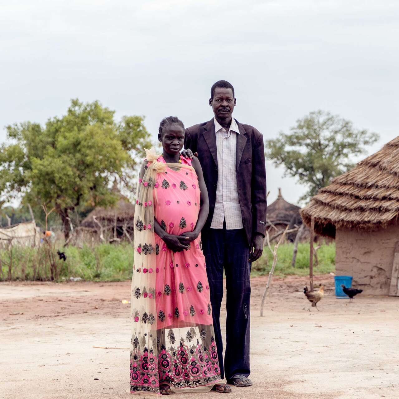 A man and a woman pose for a portrait in front of their home in South Sudan.