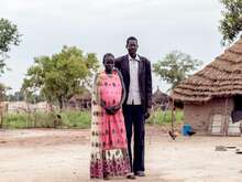 A man and a woman pose for a portrait in front of their home in South Sudan.