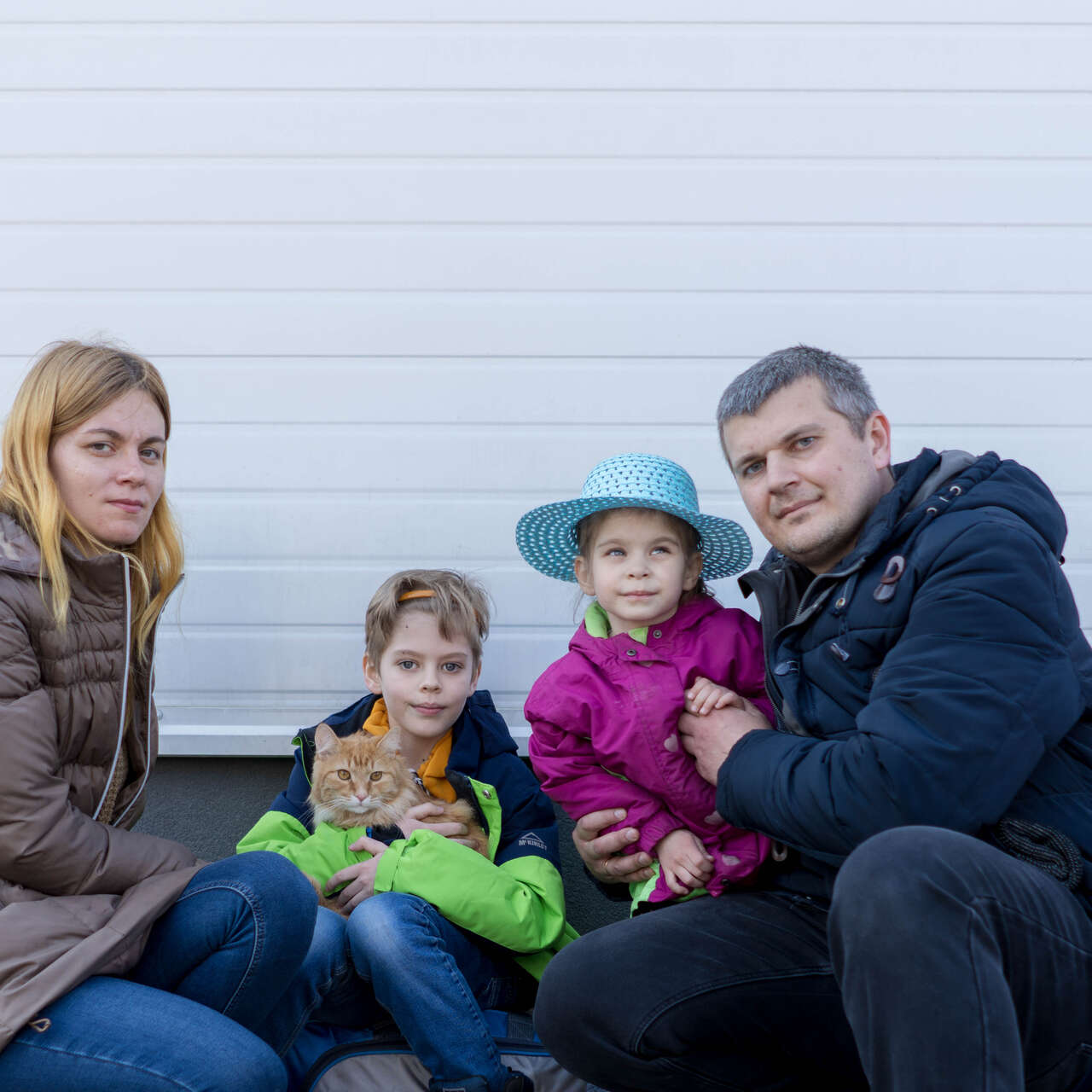 A family of four, who have recently fled war in Ukraine, pose for a picture. One of them, a young boy, holds the family's cat.