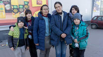 Two sisters stand together in a parklng lot. Each sister has her own two kids with her.