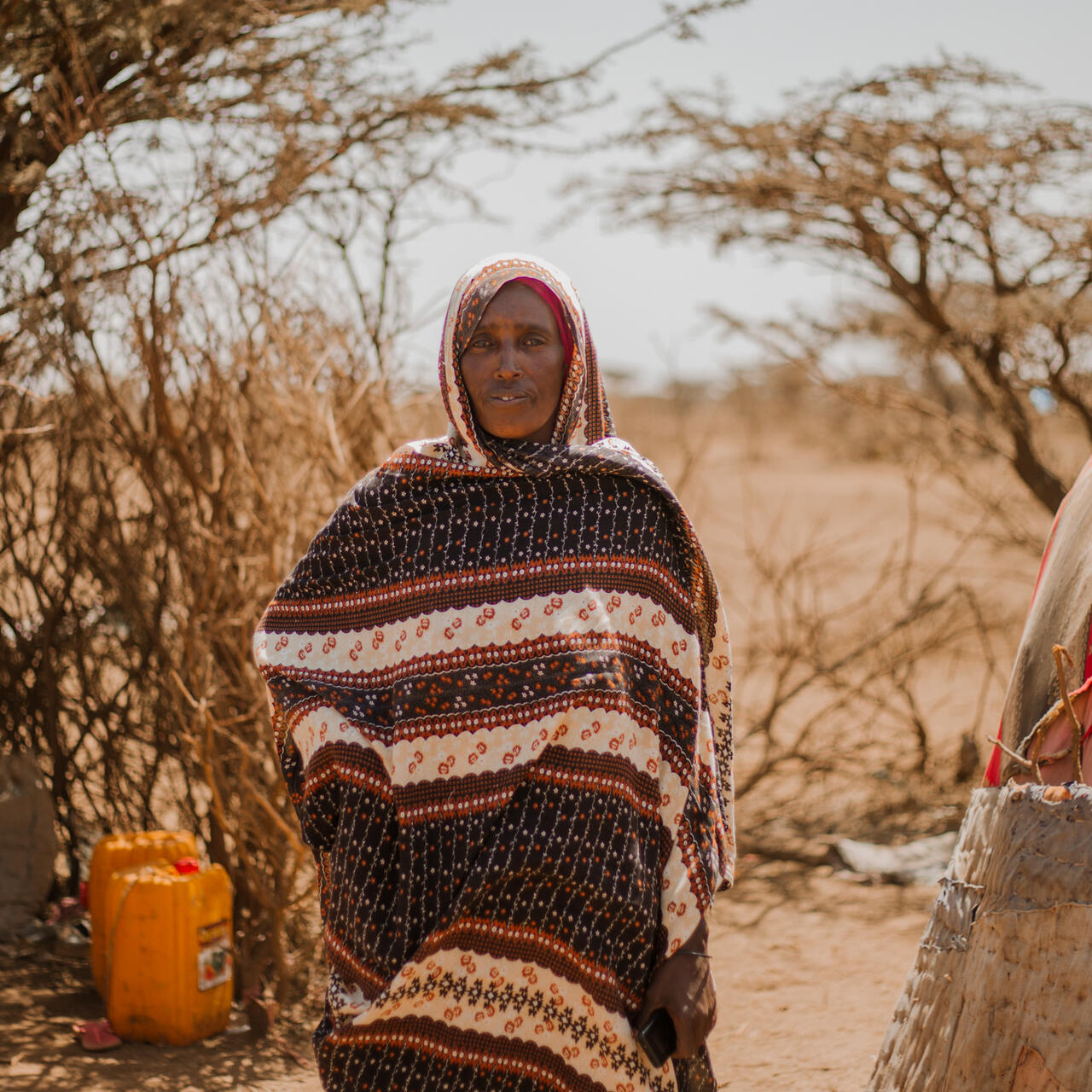 A woman poses for a photo amidst a barren landscape in Ethiopia.