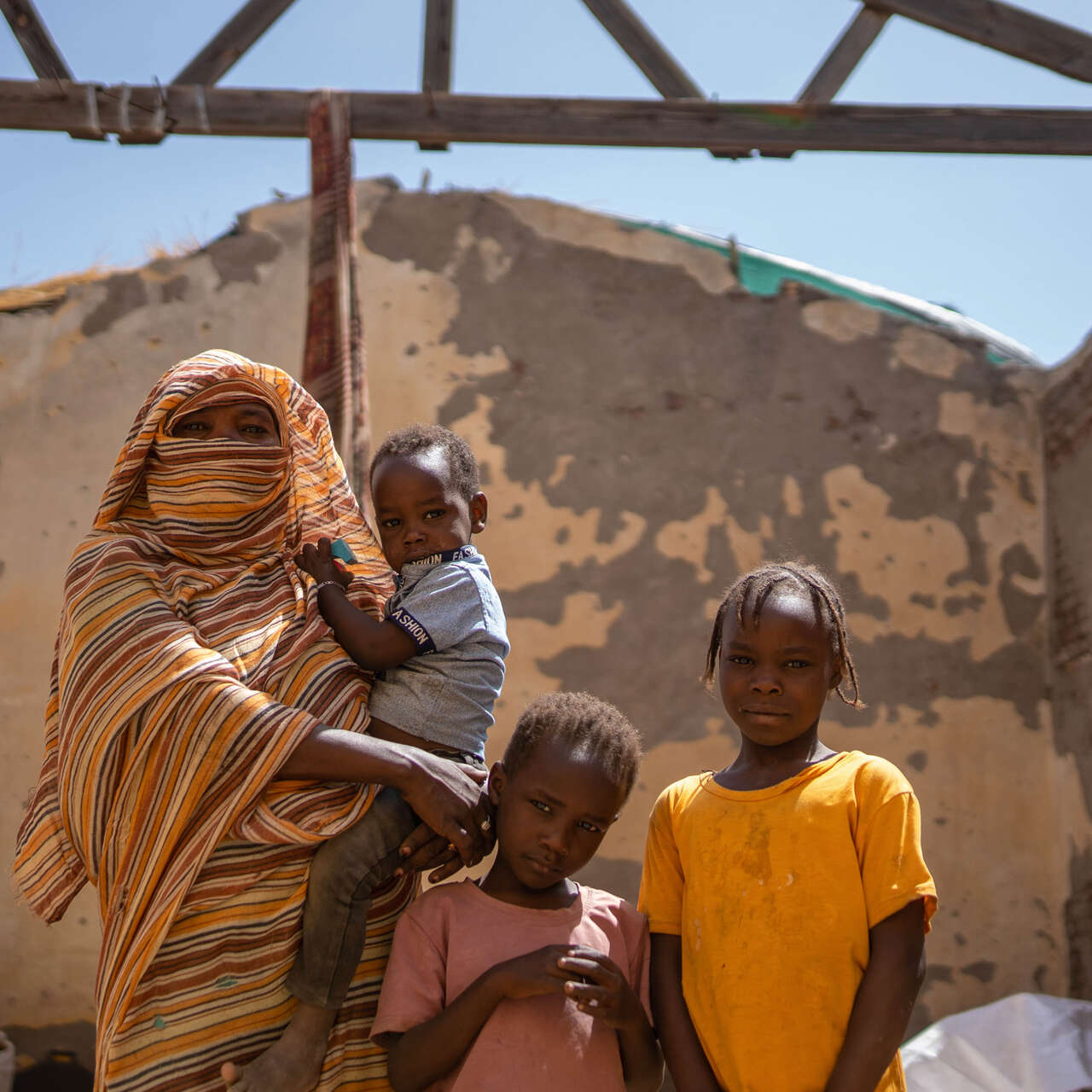 A Sudanese family pose for a photo in the ruins of a building destroyed by conflict.