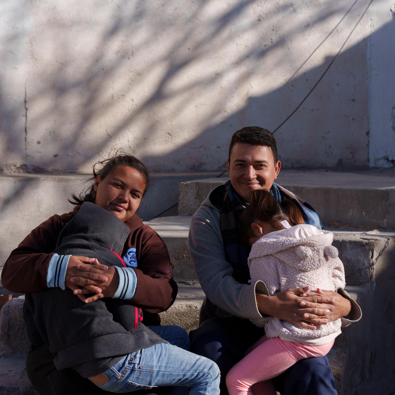 Natalia and José hold their two children. 