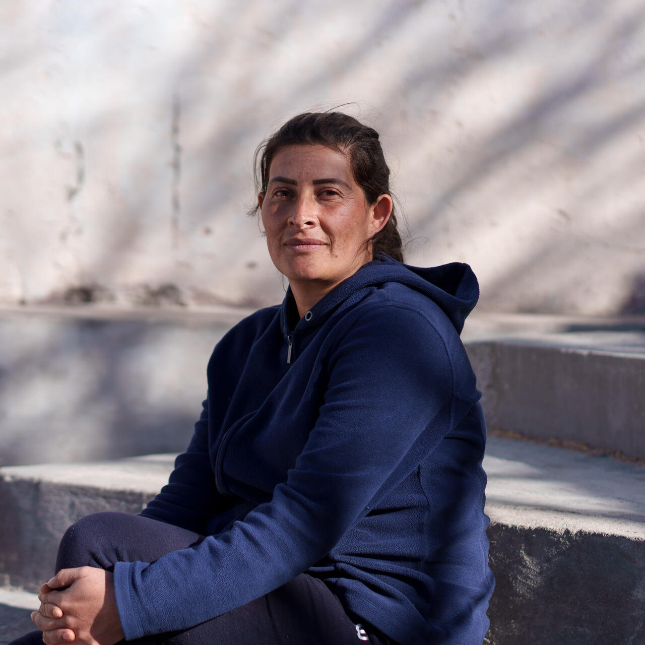 A woman sits on steps and poses for a photo.