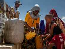 Volunteers aiding children gathering water.