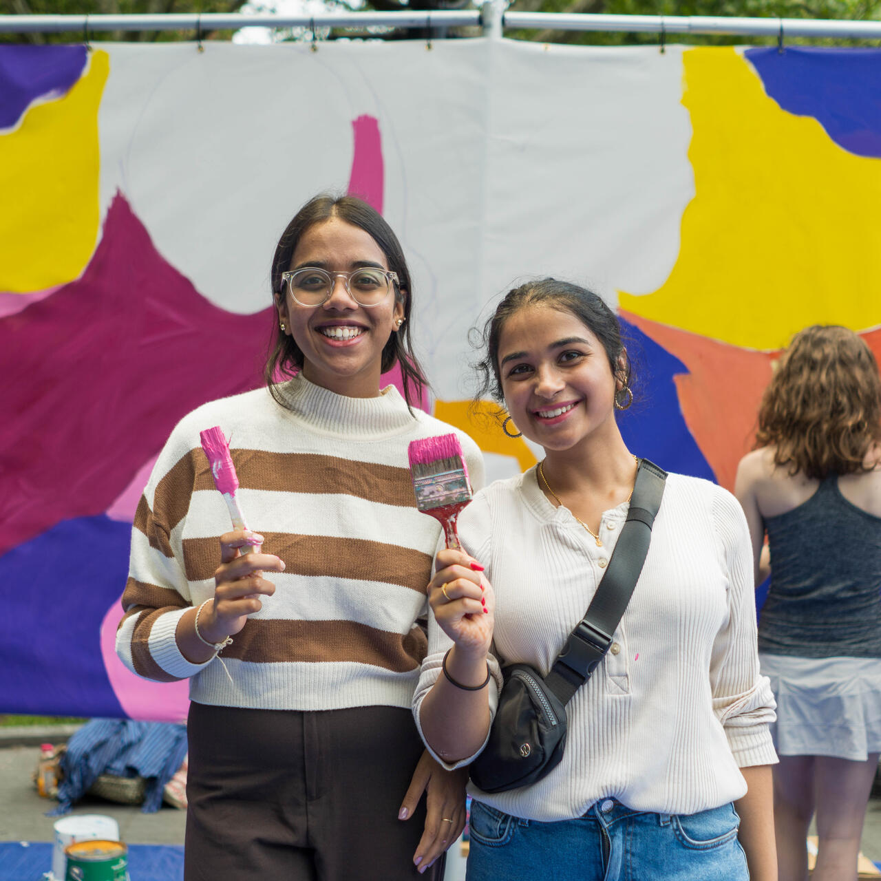 Two smiling IRC volunteers poses for a photo at an art event.