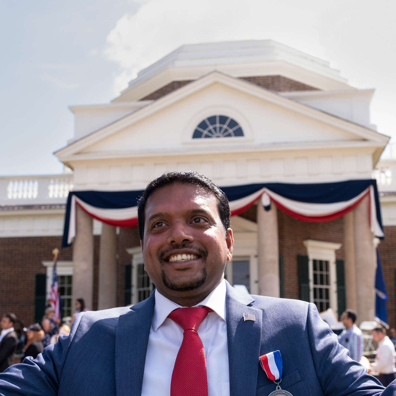 A man holds small American flags in each hand at a naturalization ceremony for new American citizens.