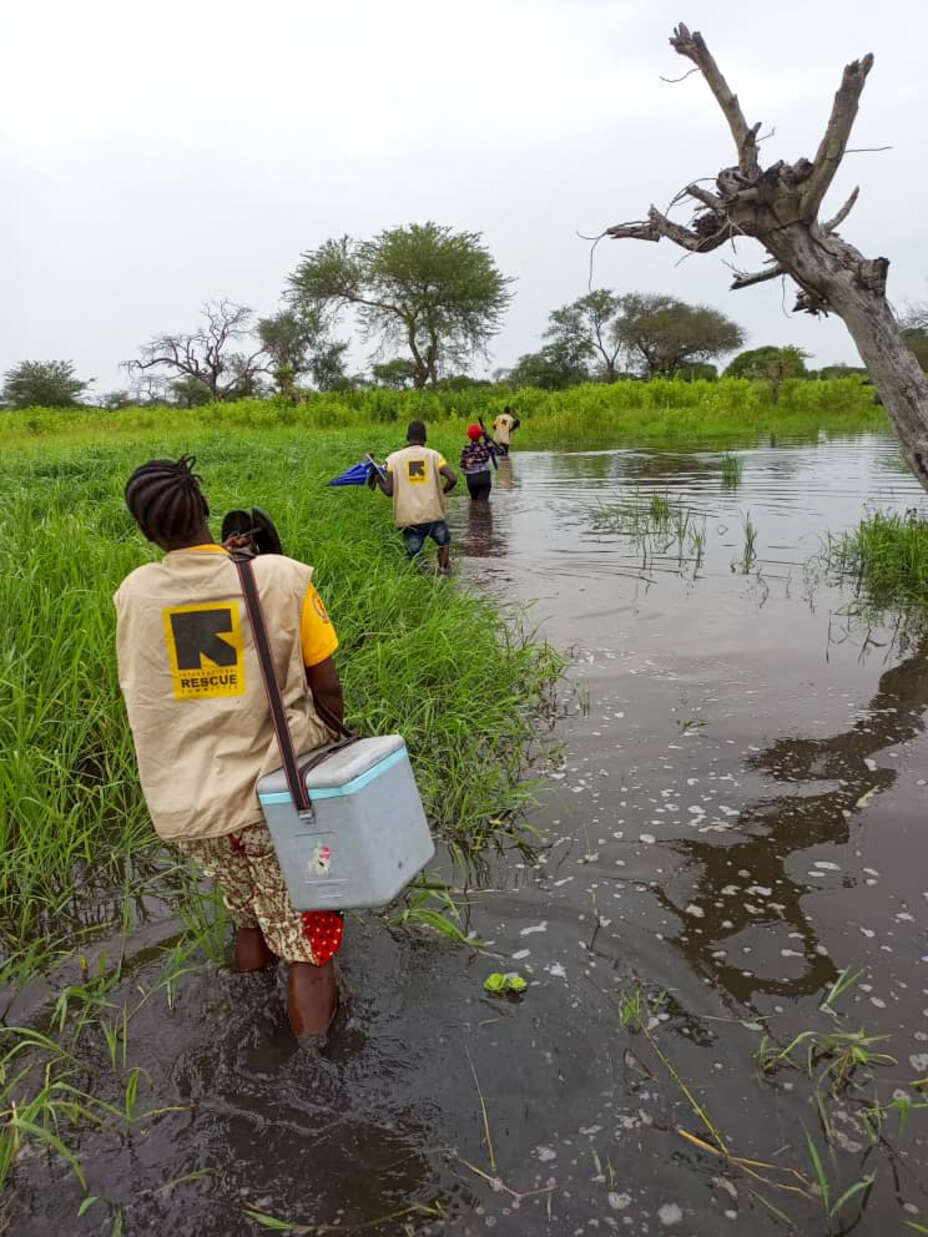 People carry medical boxes through flood waters in South Sudan