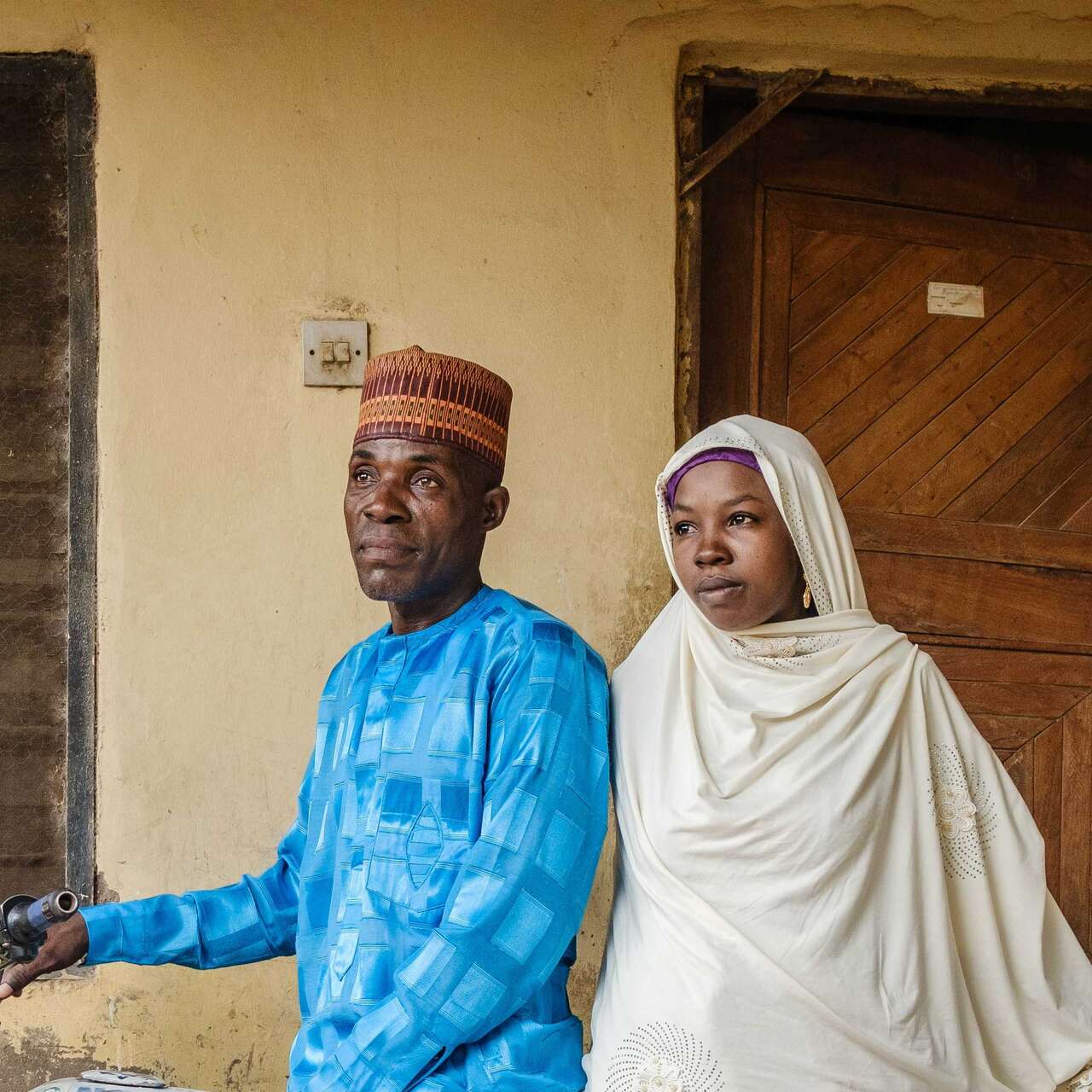 A man and a woman pose for a portrait while sitting atop a motorbike.