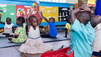 Students in Uganda hold LEGO bricks above their heads.