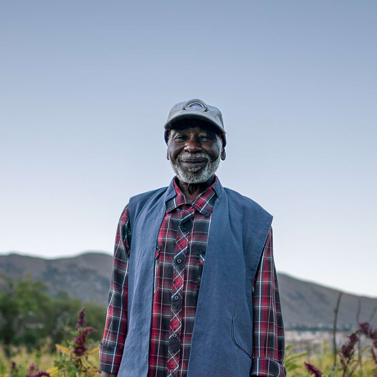 A man stands in a field and smiles while posing for a photo.