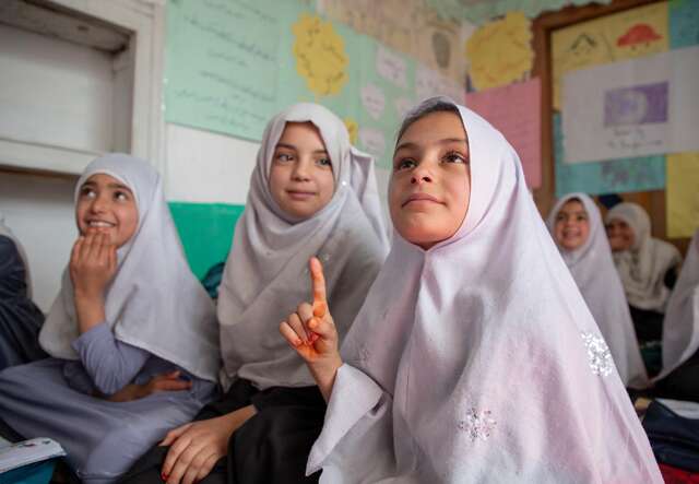 A student raises her hand to answer a question during school