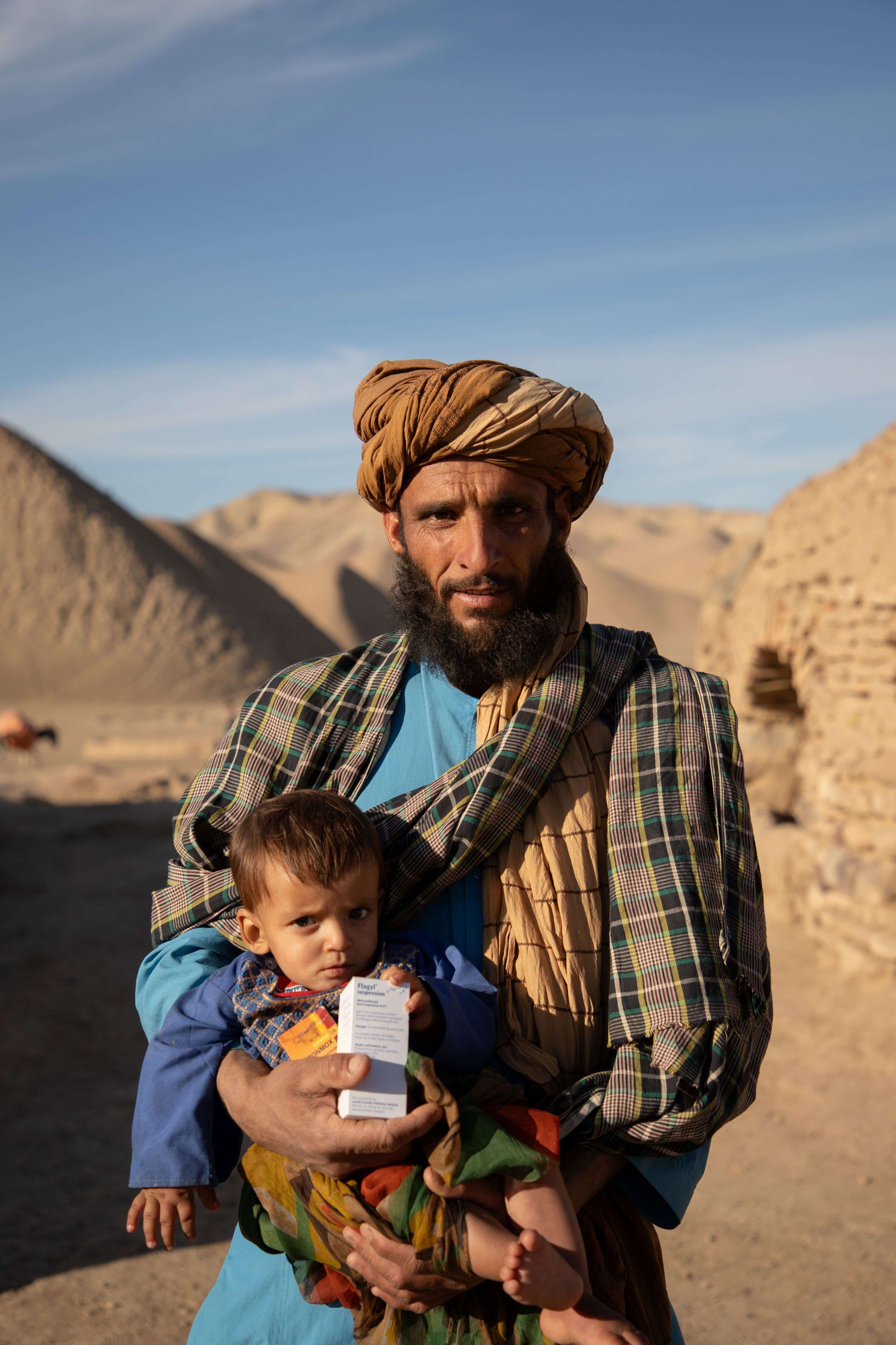 Abdul Haq holding his 10 month old son, Shams Ullah, outside the mobile health clinic after getting his medical exam.