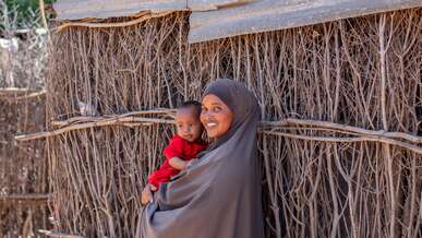 A mother holds her young child in her arms and the pair poses for a photo.