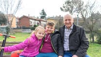 Oleksandr sits on a bench with his two grandchildren.