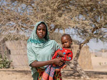 A Sudanese refugee and her one-year-old child in the dry landscape in Kafia, Chad, where IRC medical staff tested her daughter for malnutrition.