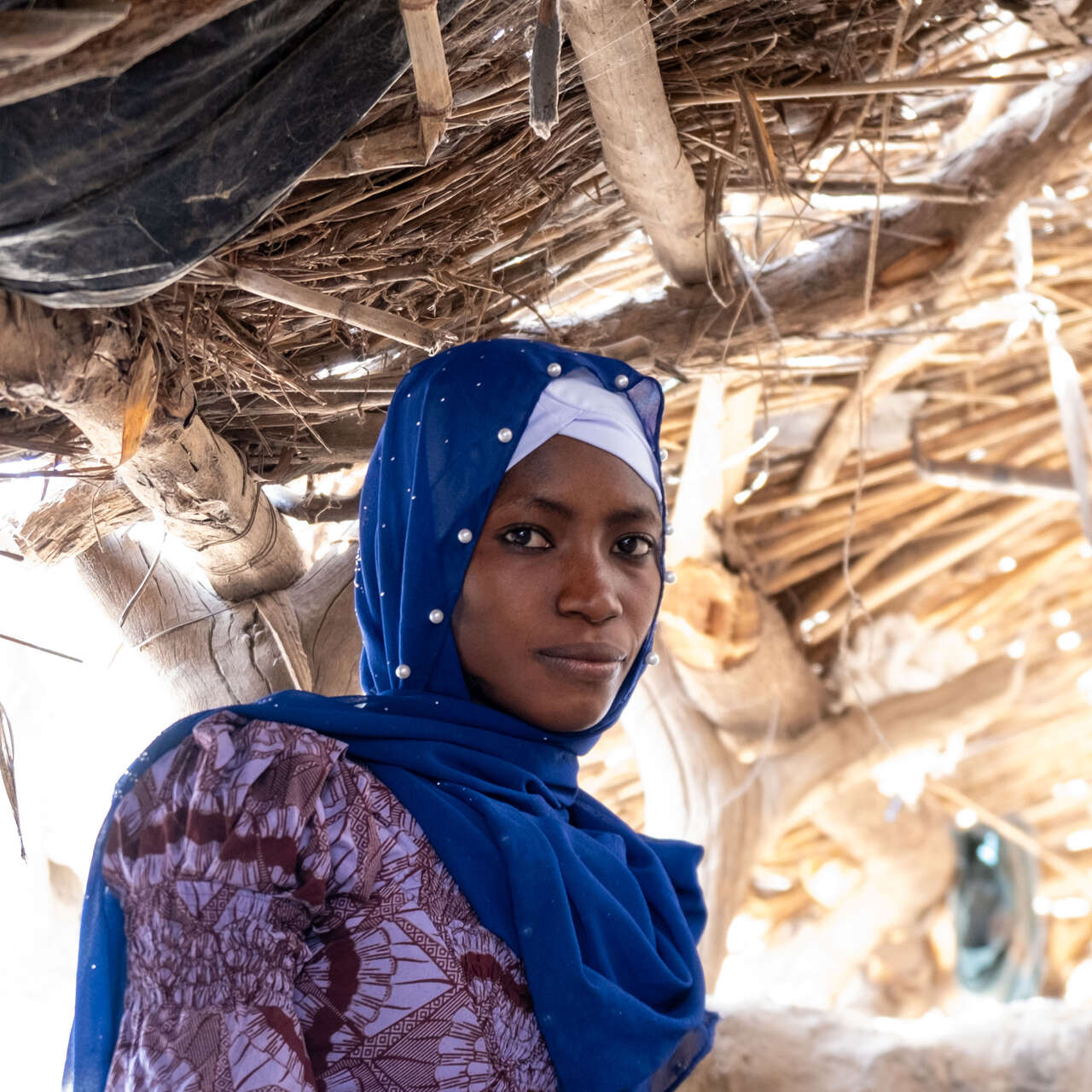 A woman poses for a photo in a makeshift shelter in Mali.