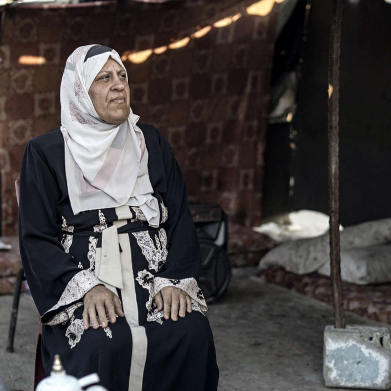 Ataf (53), sits inside her tent in Khan Younis, Gaza.