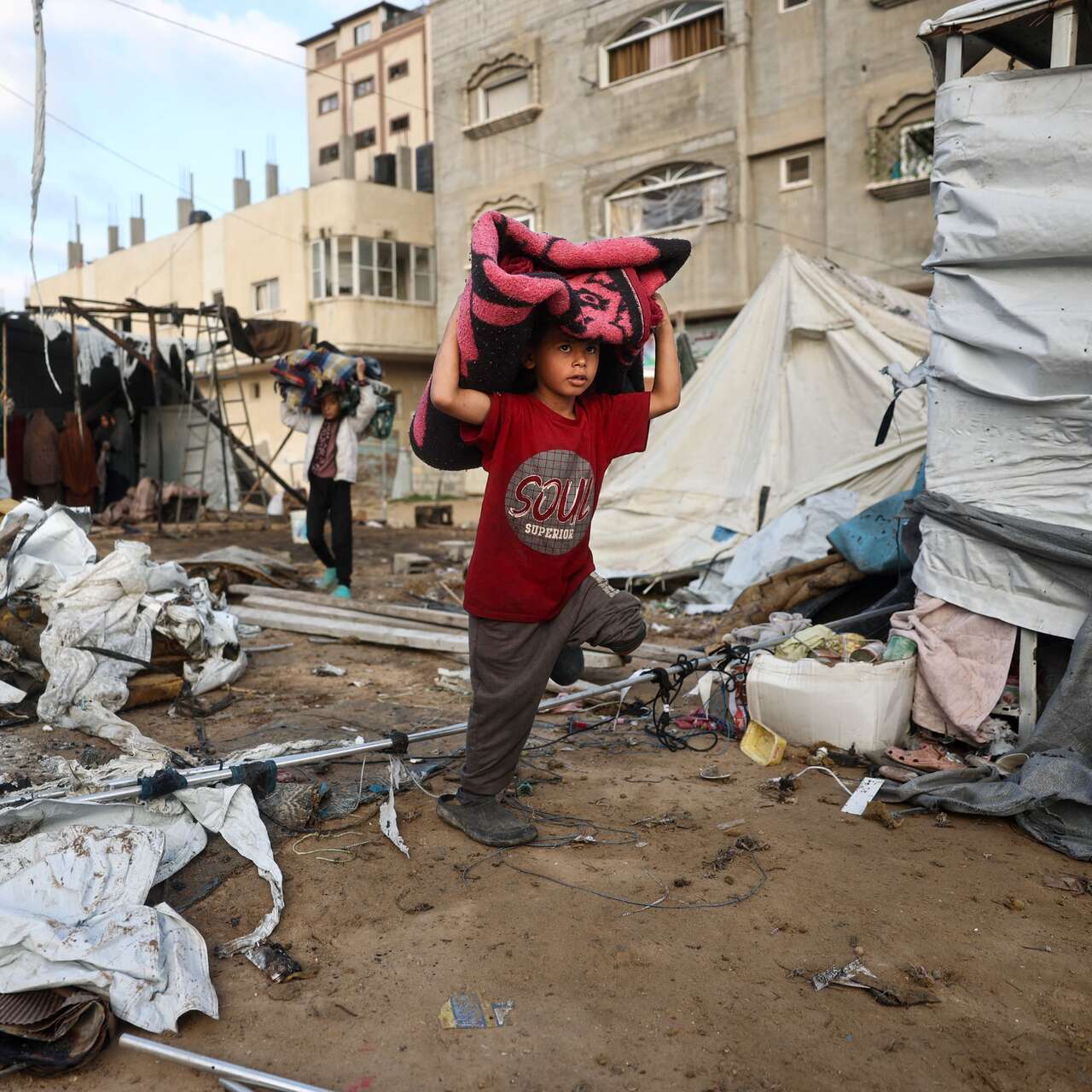 A child carries salvaged items through a refugee camp in Gaza.