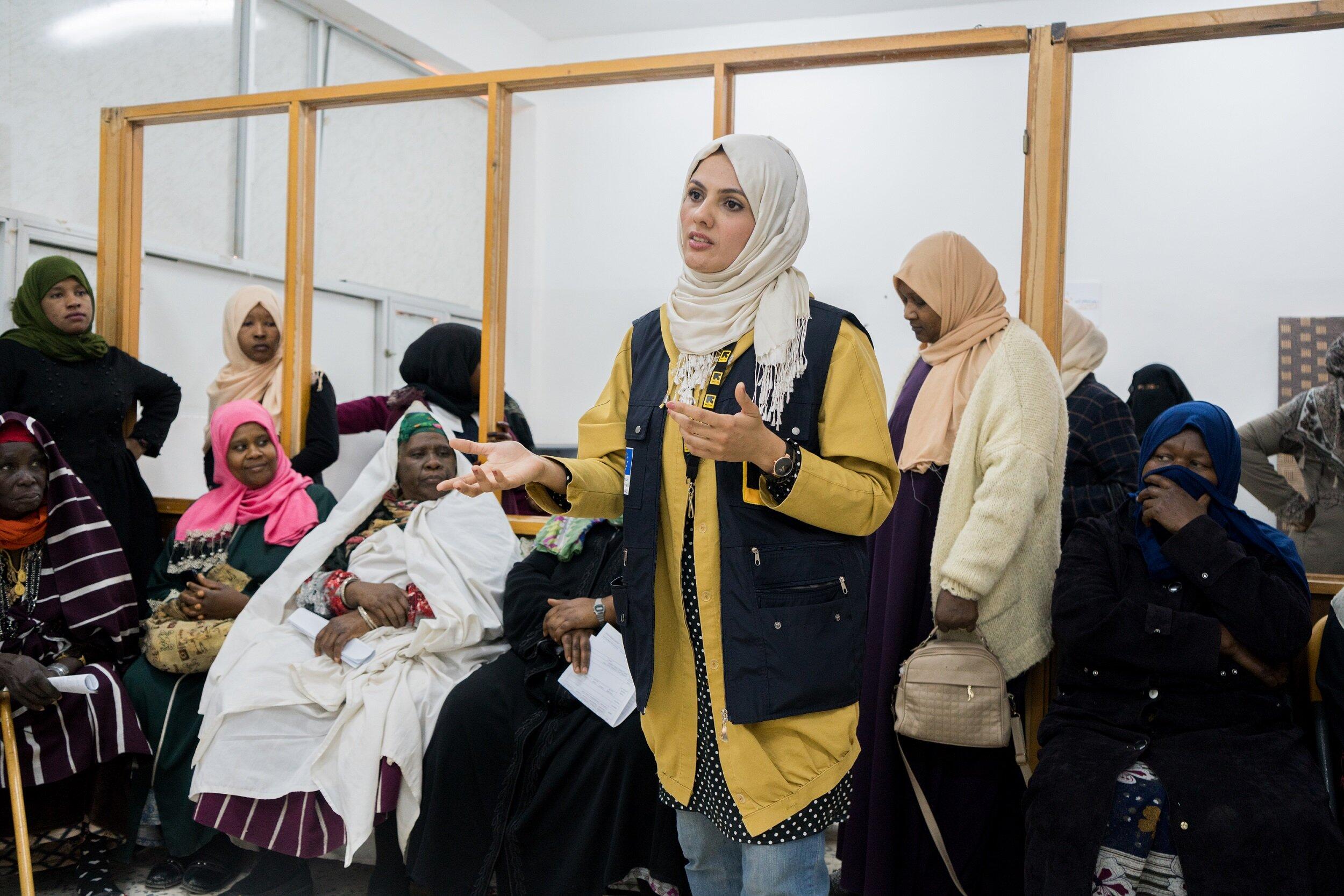 A female IRC worker in a room full of waiting women