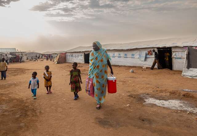 Fairuz stands outside the camp with her grandchildren.