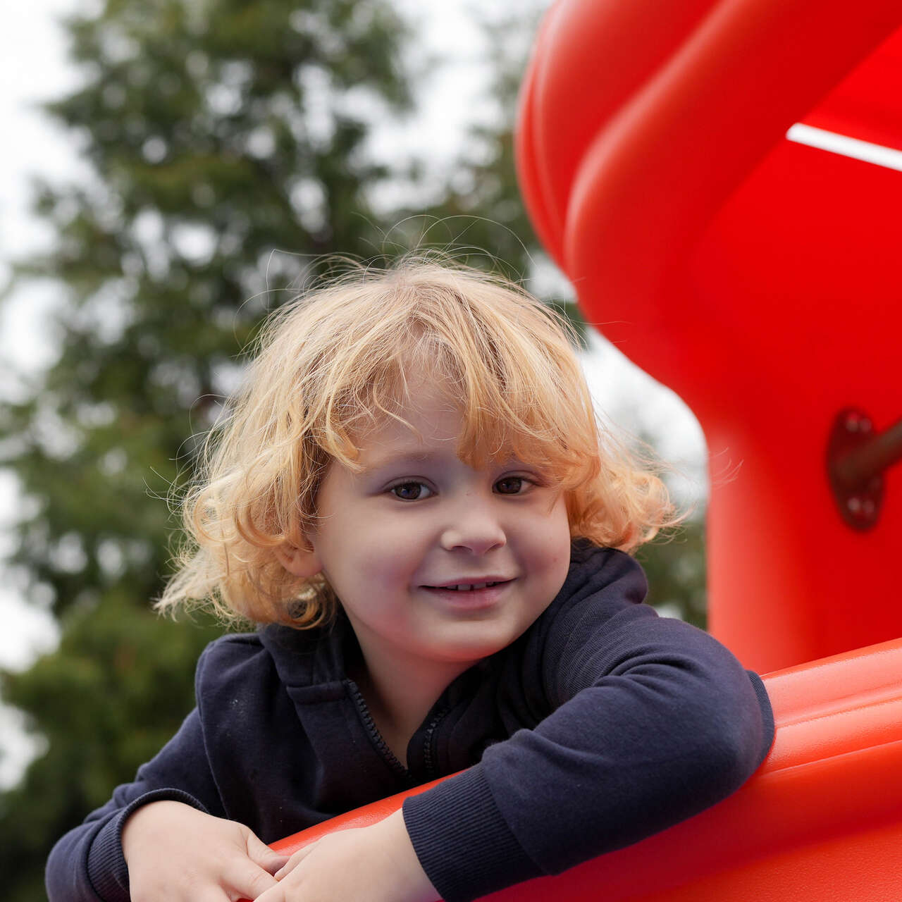 A child smiles while playing at a playground.