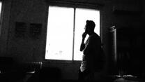 Black and white photo of Ahmad standing against a window looking outside