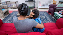 Angelina, an asylum seeker from Guatemala, sits on a red couch with her arms around her son at an IRC Welcome Center in Arizona. 