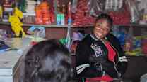 An IRC staff member meets Mercy at her provisions store in Buea, Cameroon. Together, they reflect on the progress of the business.