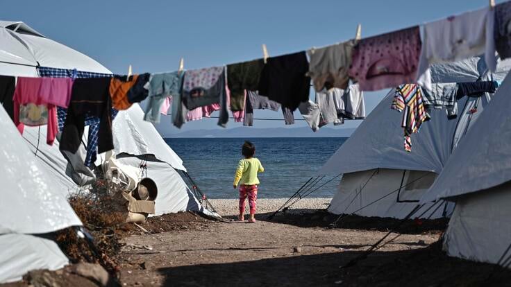 Child stands between tents at the new Lesvos camp