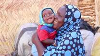 Domo holds her 8-month-old son, Ichaou, in the courtyard of their makeshift home built in the middle of the Ouallam IDP site. Oualla, Tillabéri, Niger.