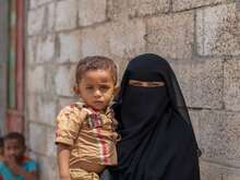 A mother holds her child in her arms. Together, they pose for a photo in Yemen.