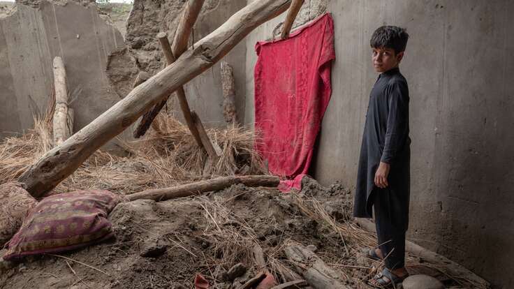 Abas, a twelve year old Afghan boy, stands in the remains of his home which was destroyed by a severe flood.