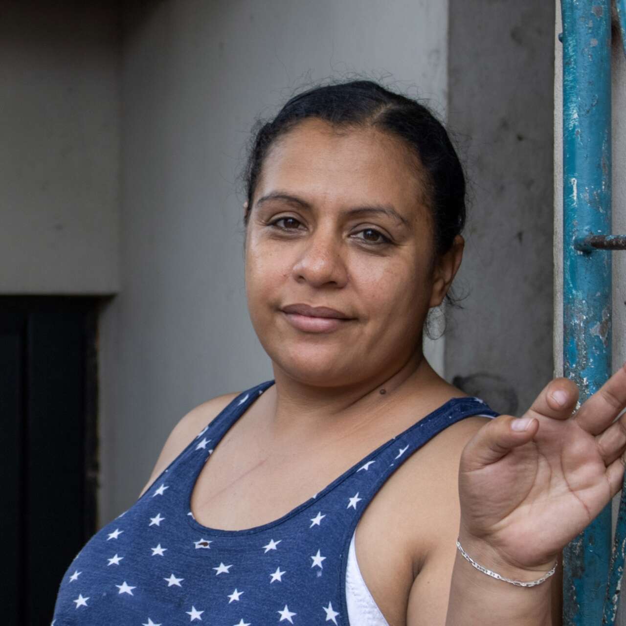 A woman stands against a wall and poses for a photo.