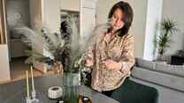 Alisa adjusts a flower centerpiece on the table of an apartment.