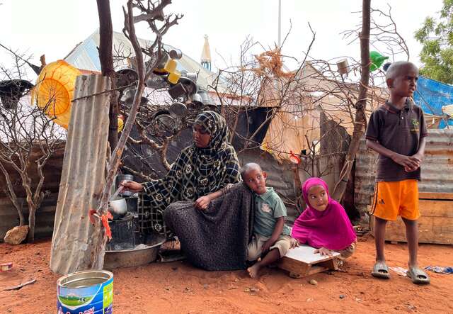 A mother prepares food for her three children in a camp for internally displaced Somalis.