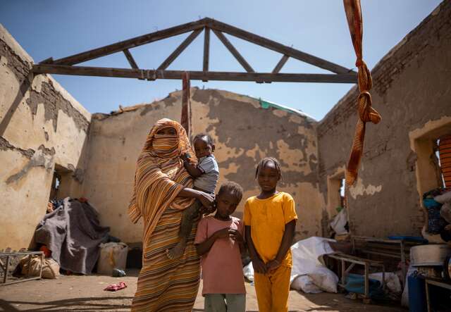 Altuma stands in her temporary house with her three children.