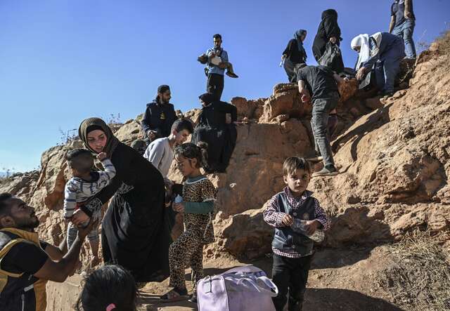Families climb a rocky path as they flee violence in Lebanon.