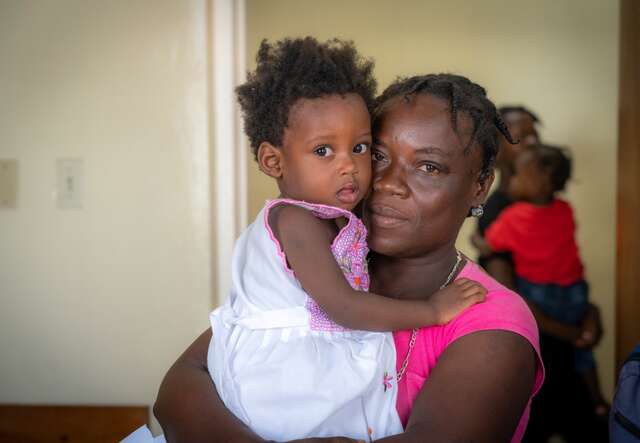 A Haitian mother holds her young daughter in her arms.