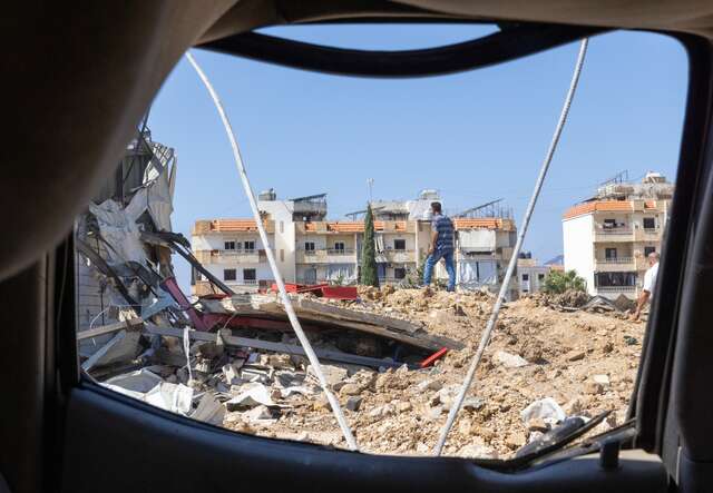 A man walks across the rubble of a destroyed building.