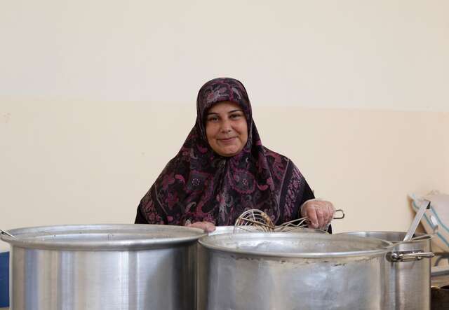 A woman smiles while cooking.
