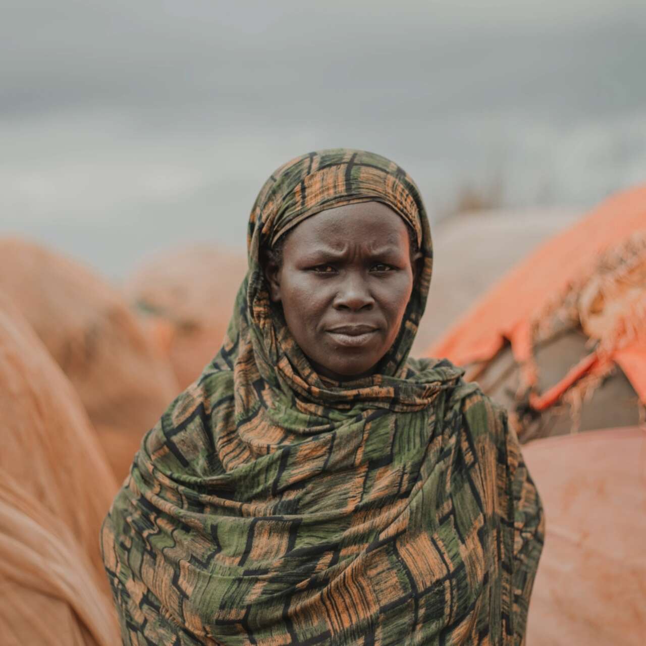 A woman poses solemnly for a photo outside of a makeshift shelter in Somalia.